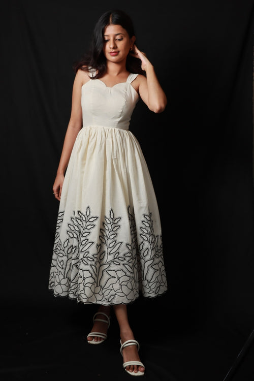 A light colored with mid length fitted bodice and flared skirt with distinctive embroidered