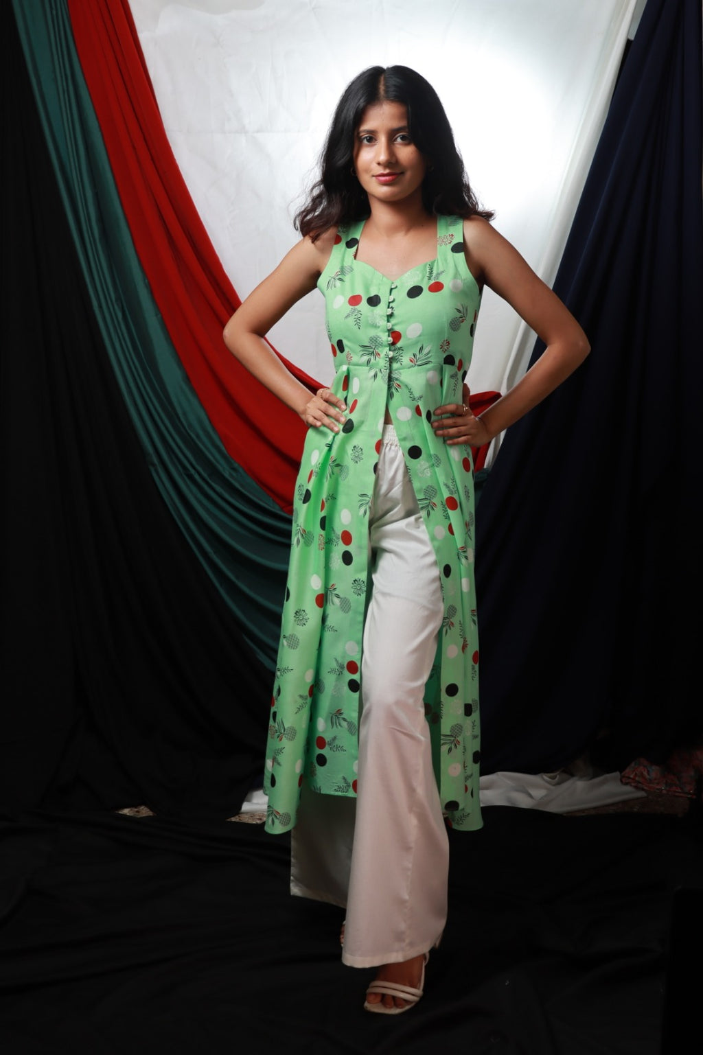 Light green sleeveless knee length kurthi with front slit and button detailing paired with wide leg white cream pant